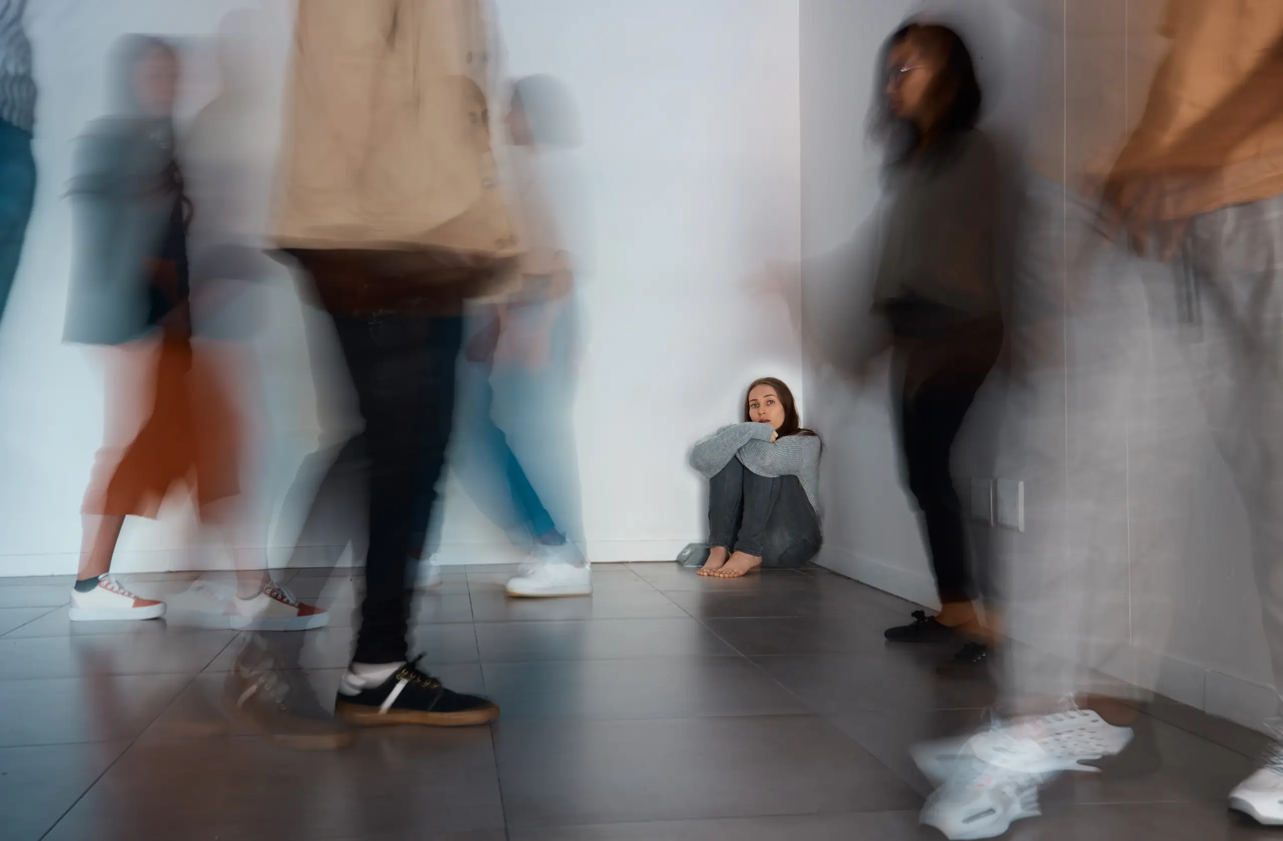 A person sitting alone with blurred people in the background representing disconnection